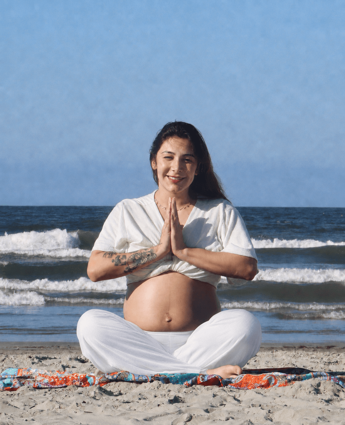 Natália grávida meditando em frente ao mar