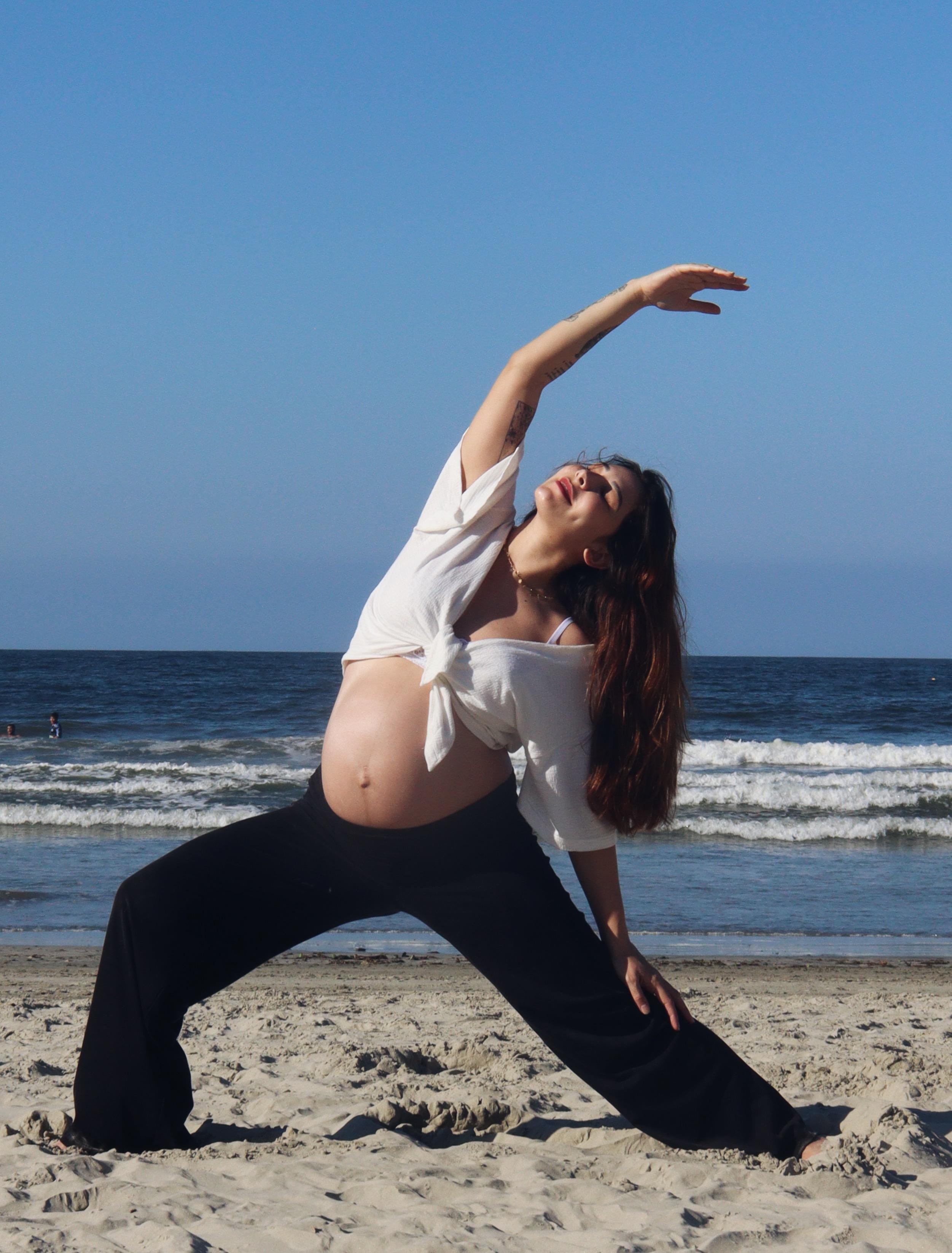 Natália grávida praticando yoga na praia